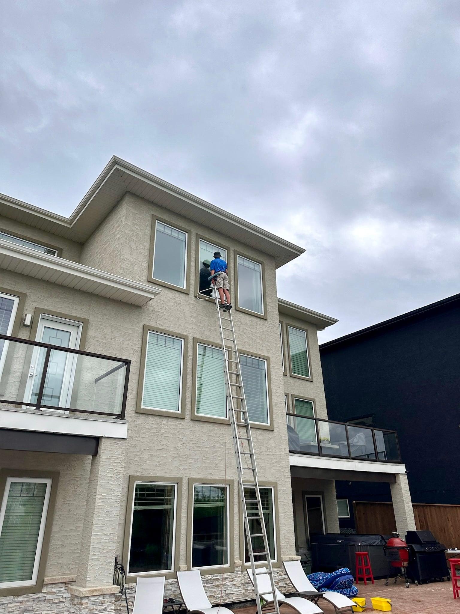 Bubble Brothers team member cleaning exterior windows on a Winnipeg home